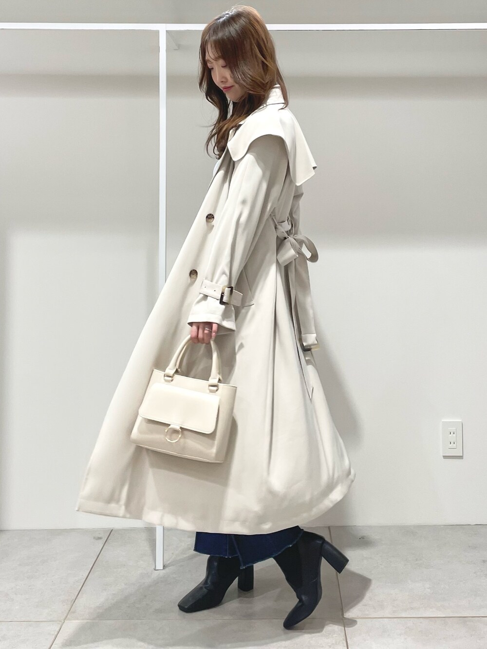 ホワイト系のハンドバッグ、ブラック系のブーツ、ブルー系のニット/セーターを着用したレディースの冬コーディネートの4枚目の写真