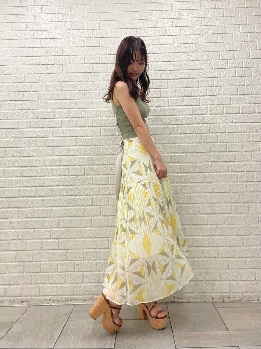 ベージュ系のサンダル、イエロー系のスカート、ベージュ系のニット/セーターを着用したレディースの夏コーディネートの3枚目の写真