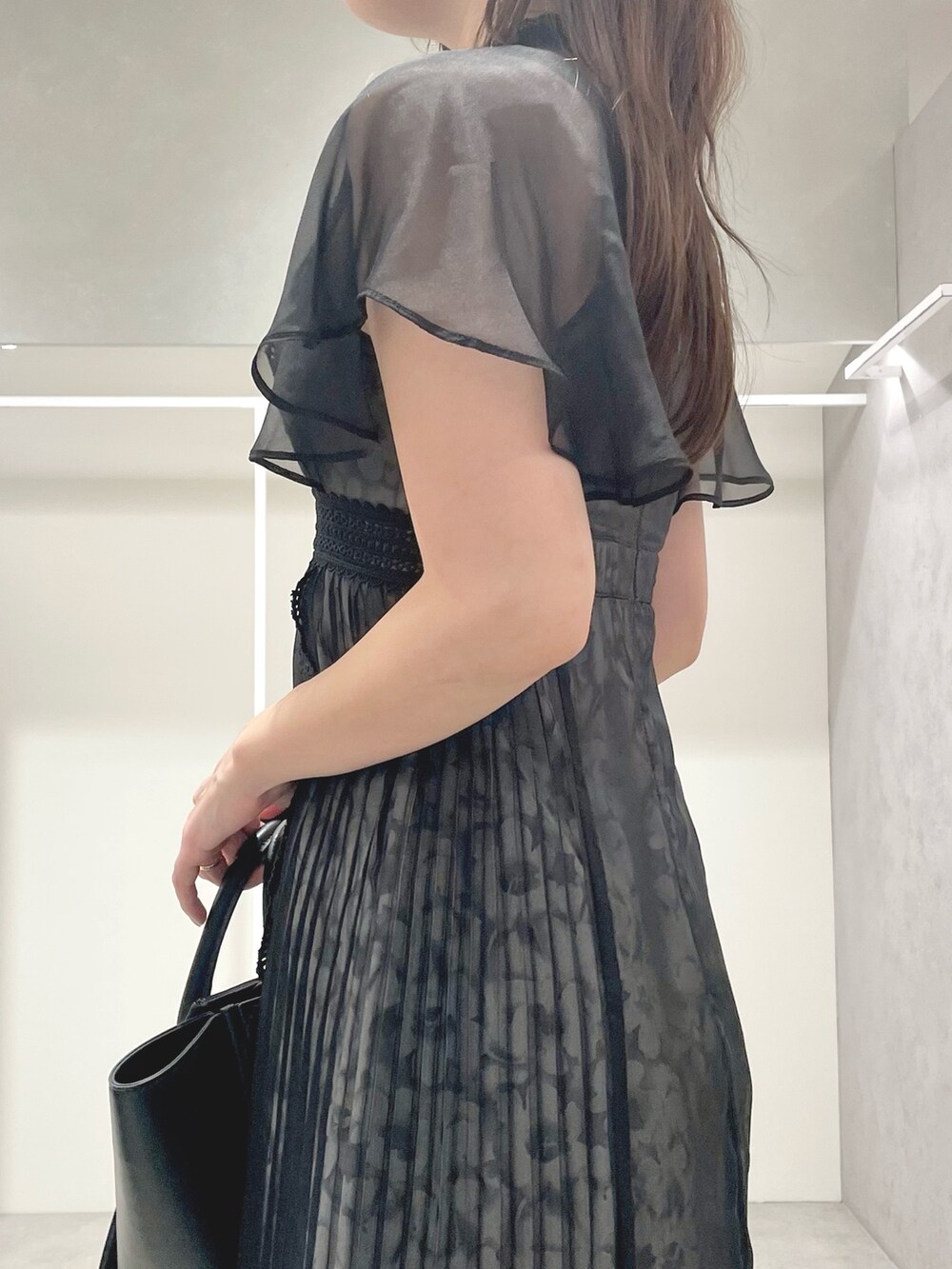 ブラック系のワンピース、ブラック系のトートバッグ、ブラック系のサンダルを着用したレディースの夏コーディネートの7枚目の写真