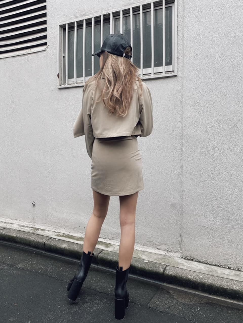 ベージュ系のスカート、ベージュ系のトレンチコート、ブラック系のブーツを着用したレディースの秋コーディネートの3枚目の写真