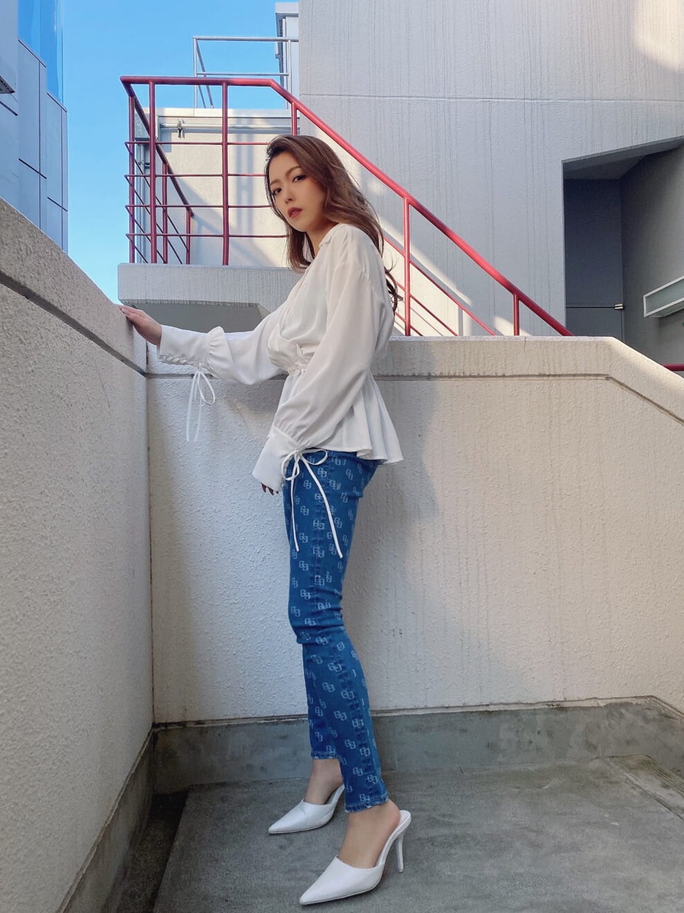 ブルー系のデニムパンツ、ホワイト系のパンプス、ホワイト系のシャツ/ブラウスを着用したレディースの冬コーディネートの2枚目の写真