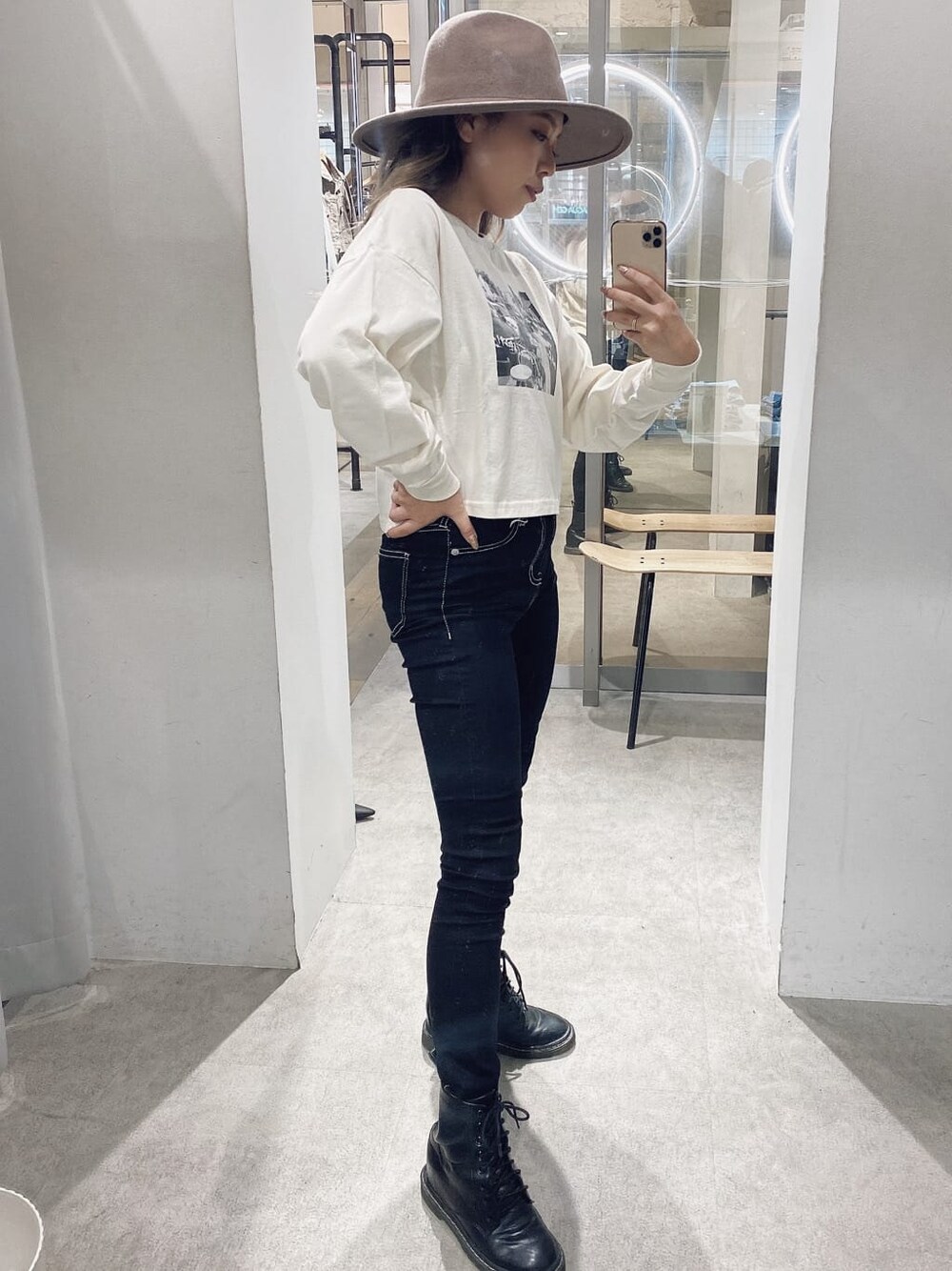 ブラック系のデニムパンツ、ブラック系のブーツ、ホワイト系のTシャツ/カットソーを着用したレディースの夏コーディネートの2枚目の写真