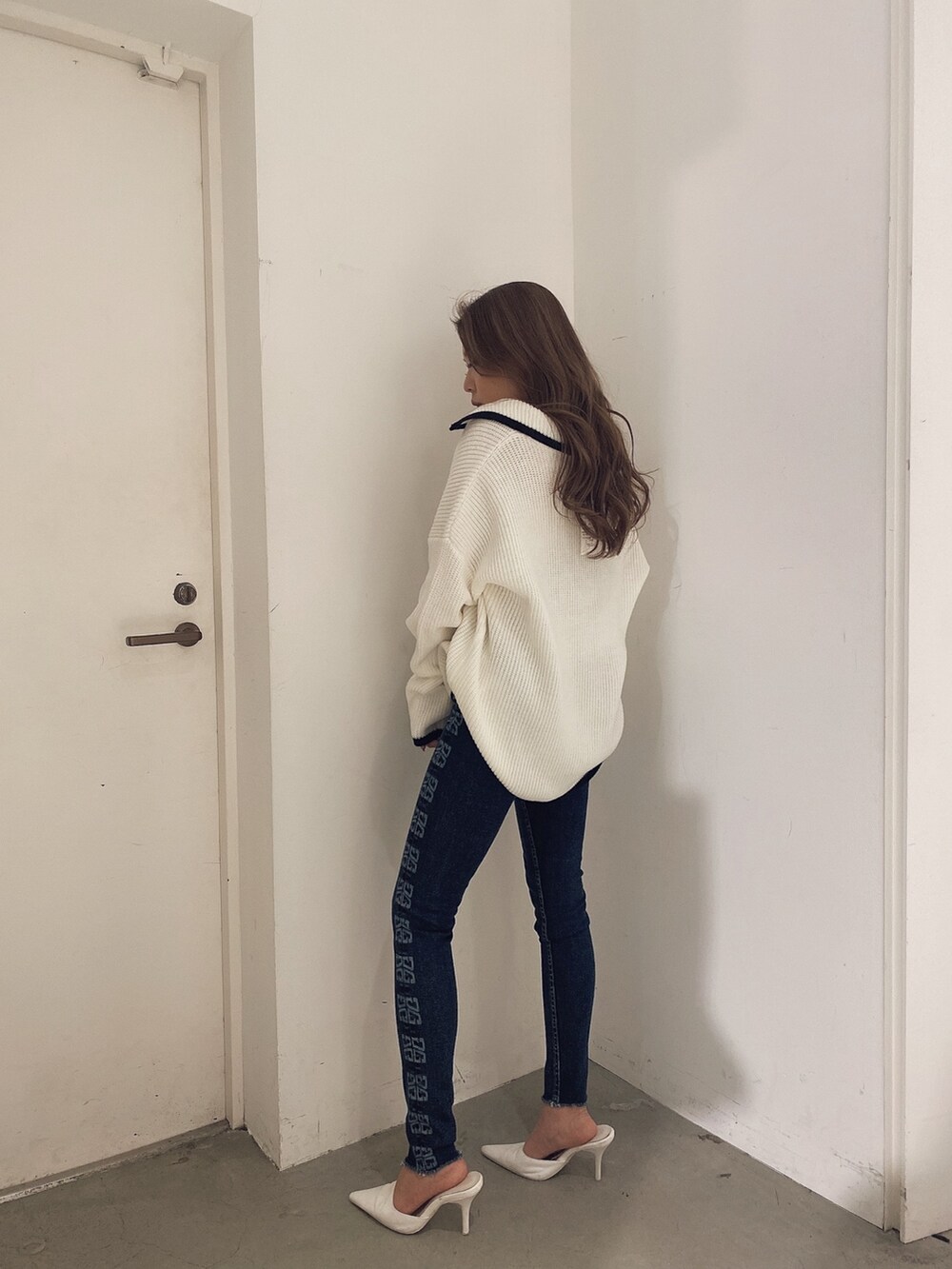 ホワイト系のニット/セーター、ブルー系のパンツ、ホワイト系のパンプスを着用したレディースの冬コーディネートの3枚目の写真