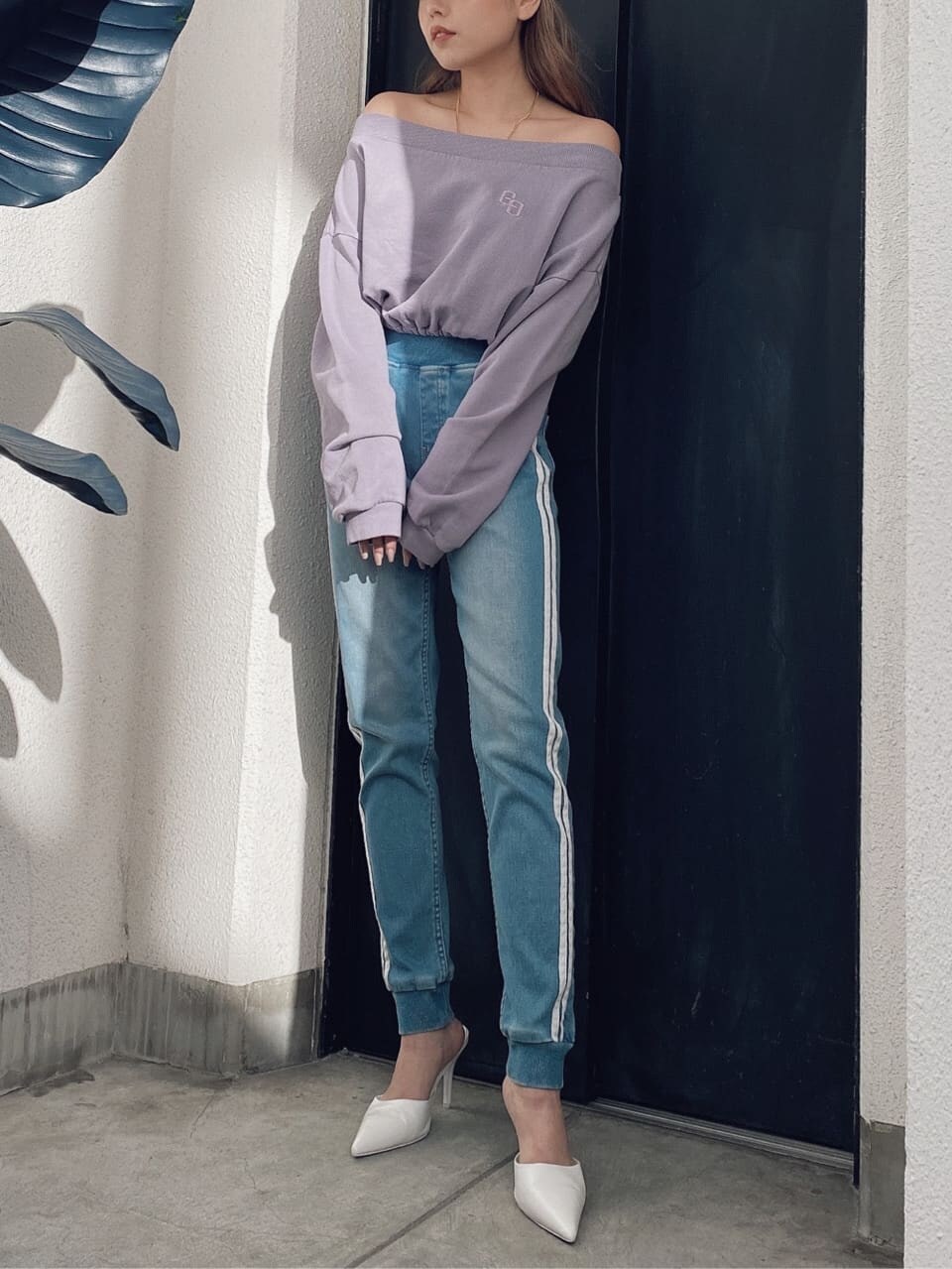 パープル系のスウェット、ブルー系のデニムパンツ、ホワイト系のパンプスを着用したレディースの冬コーディネートの3枚目の写真