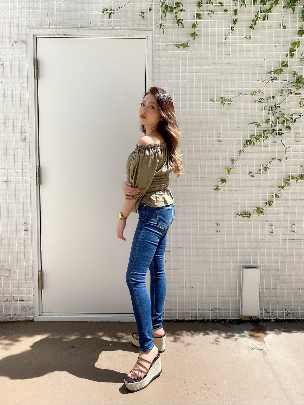 ブルー系のデニムパンツ、ベージュ系のシャツ/ブラウス、ブラック系のサンダルを着用したレディースの春コーディネートの2枚目の写真