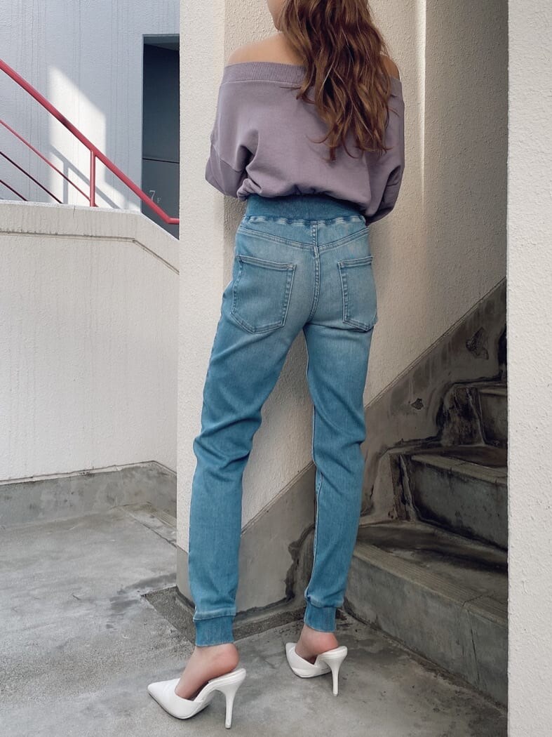 パープル系のスウェット、ブルー系のデニムパンツ、ホワイト系のパンプスを着用したレディースの冬コーディネートの2枚目の写真