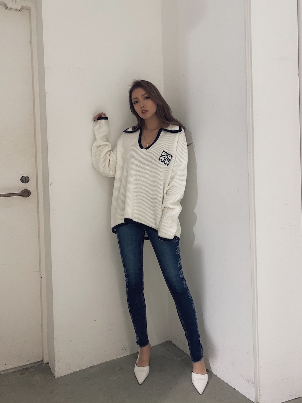 ホワイト系のニット/セーター、ブルー系のパンツ、ホワイト系のパンプスを着用したレディースの冬コーディネートの2枚目の写真