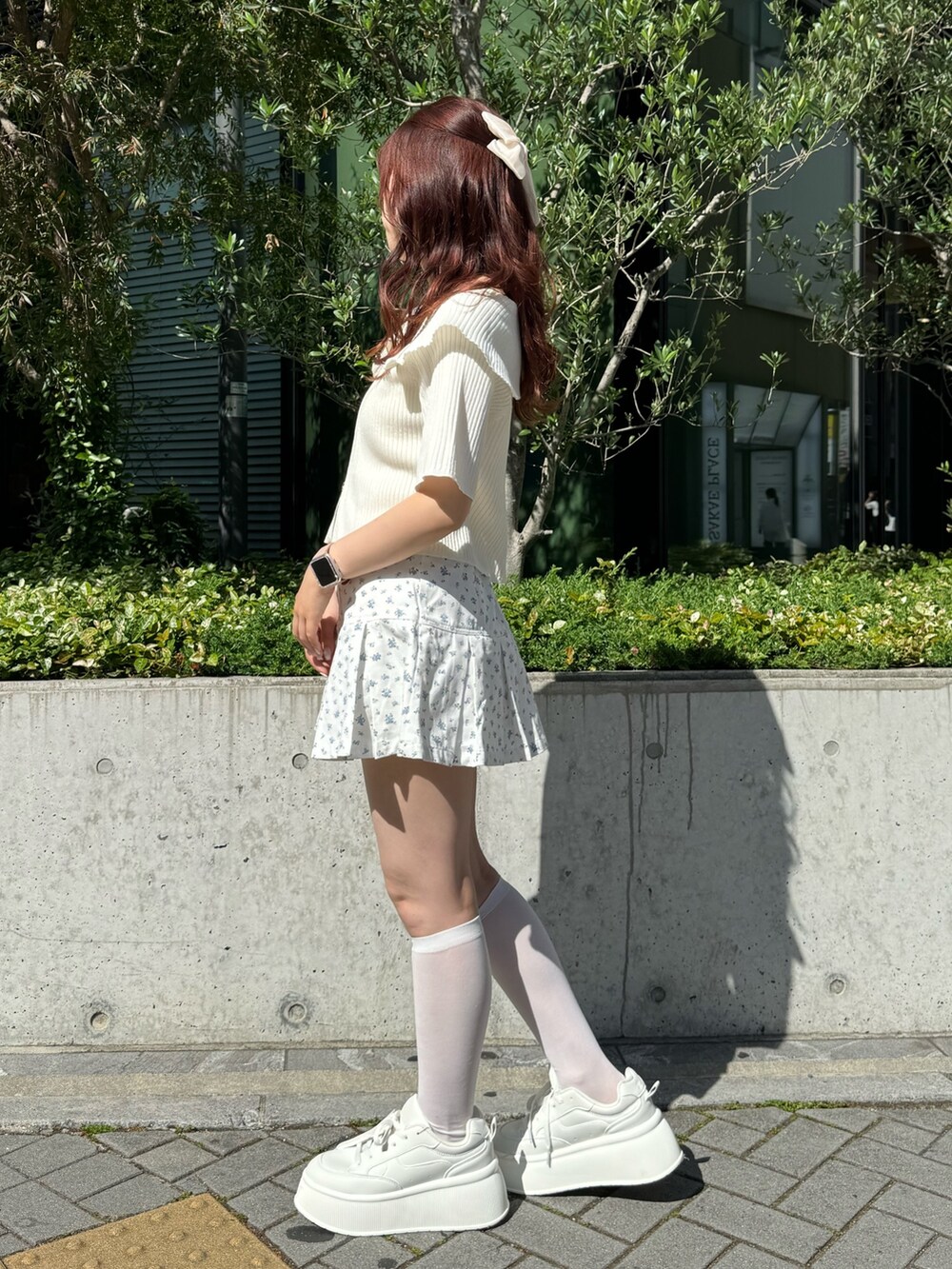 ホワイト系のニット/セーター、ブルー系のスカート、ホワイト系のスニーカーを着用したレディースの春コーディネートの2枚目の写真