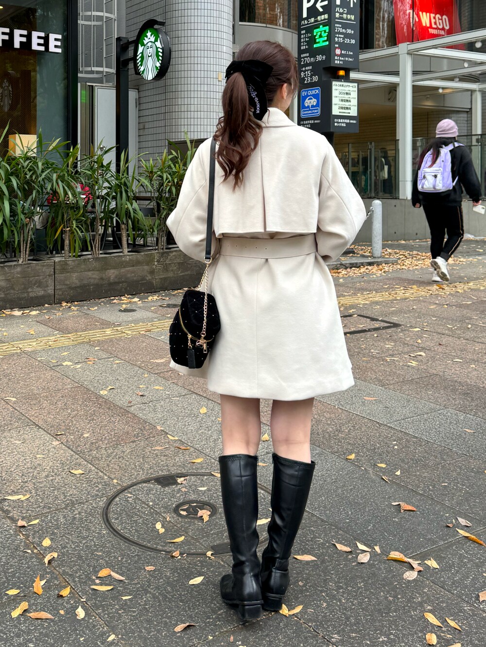 ホワイト系のピーコート、ブラック系のショルダーバッグを着用したレディースの冬コーディネートの2枚目の写真