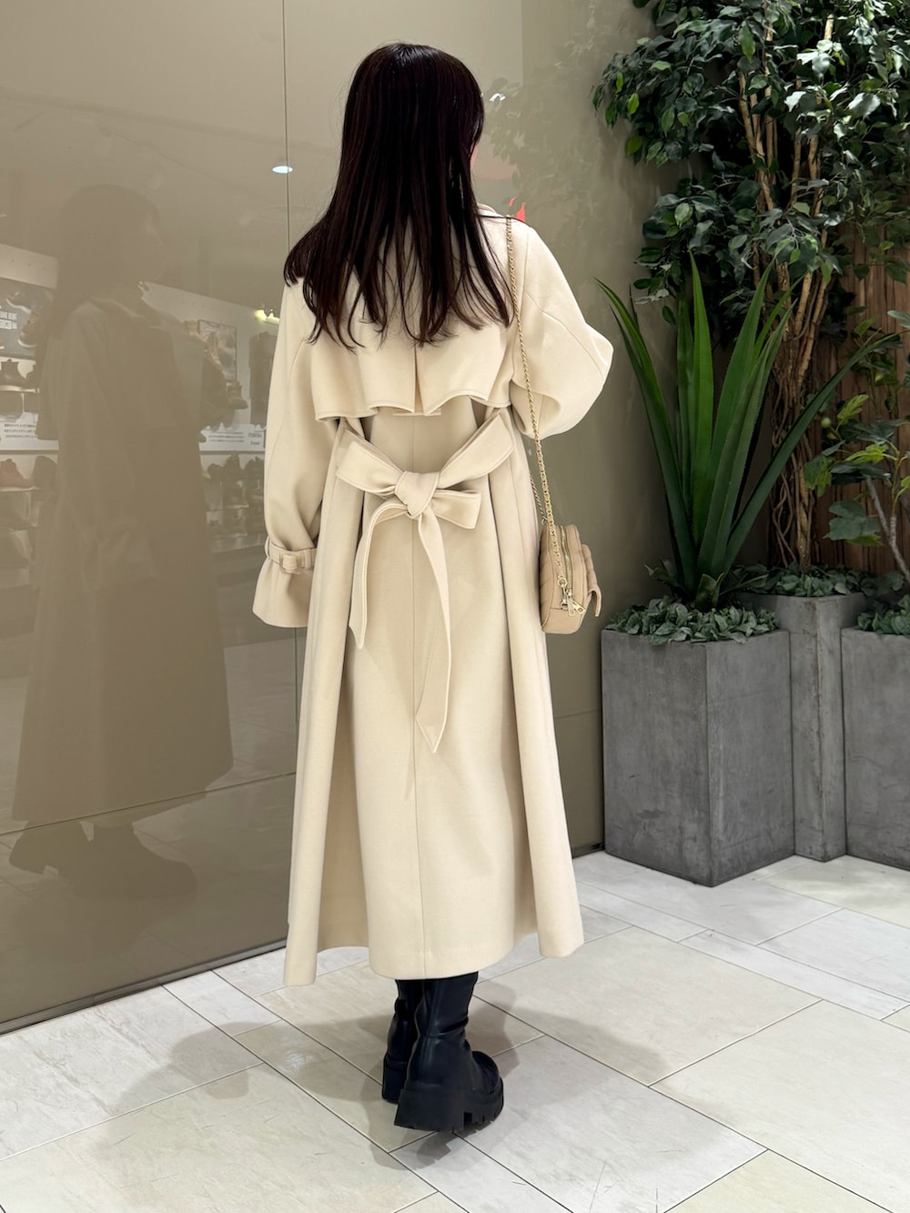 ホワイト系のステンカラーコート、ベージュ系のショルダーバッグ、ホワイト系のニット/セーターを着用したレディースの冬コーディネートの4枚目の写真