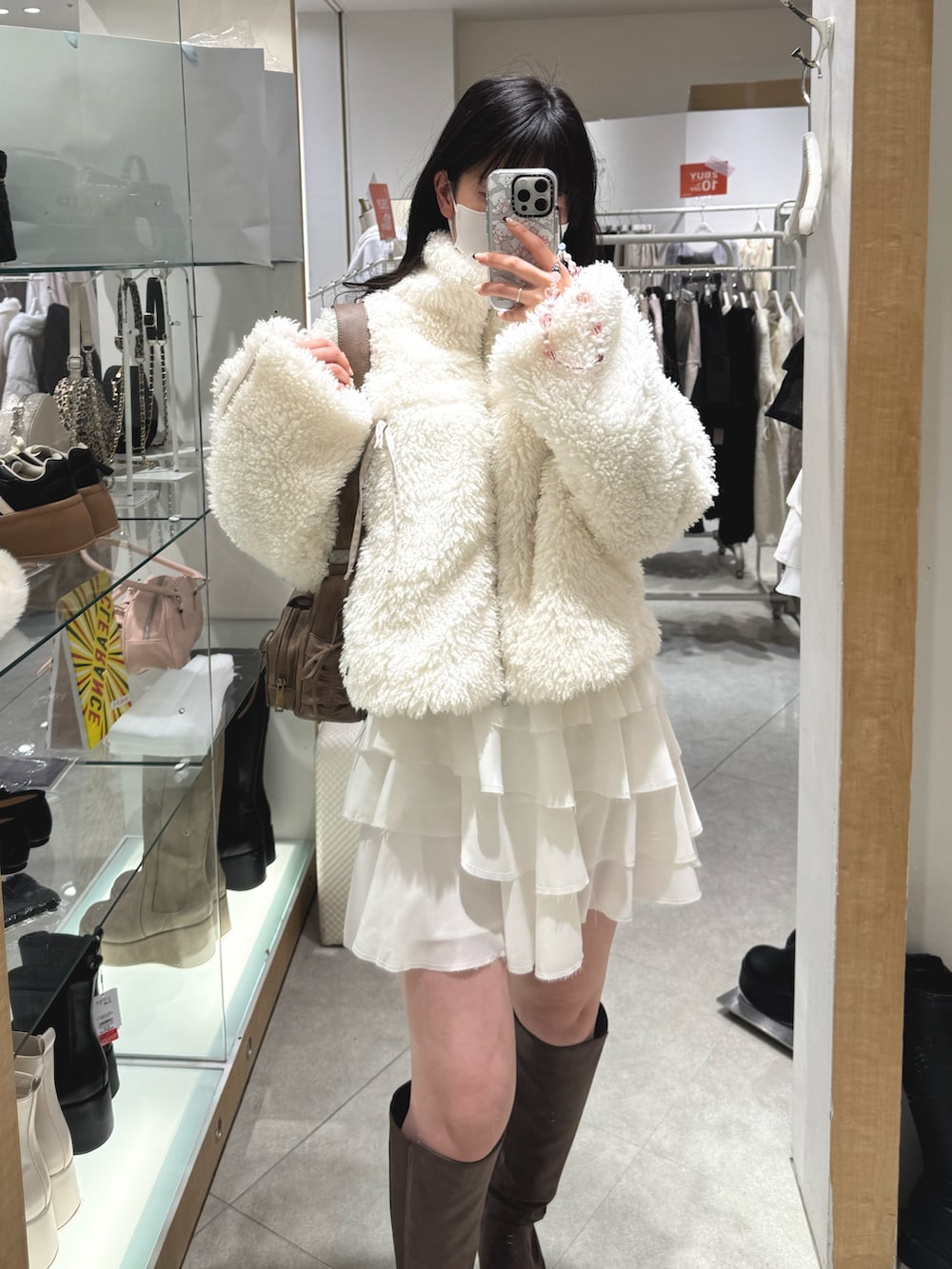 ホワイト系のブルゾン、ホワイト系のスカート、ブラウン系のショルダーバッグを着用したレディースの冬コーディネートの2枚目の写真