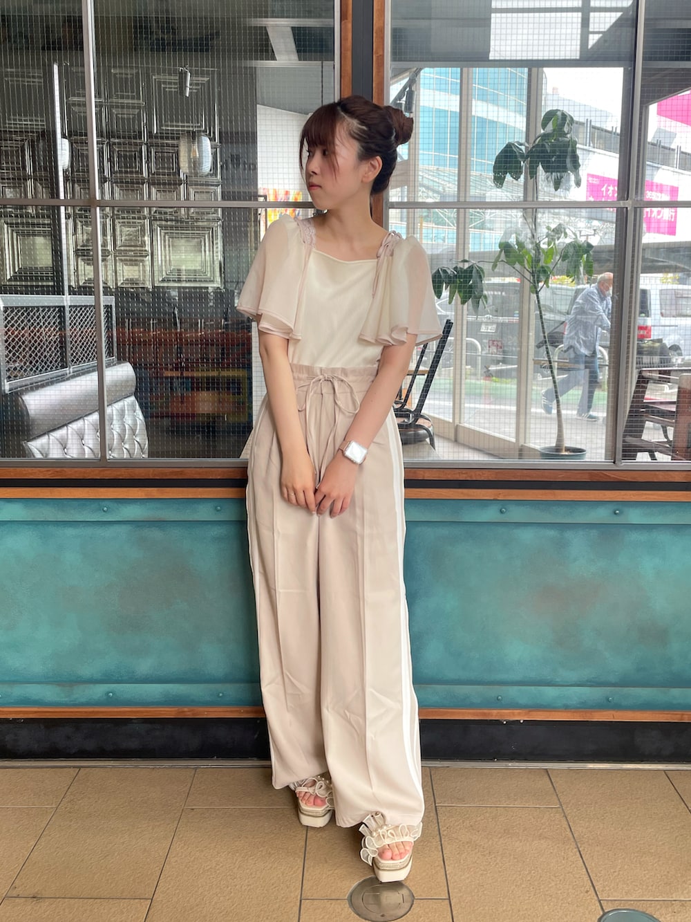 ホワイト系のTシャツ/カットソー、ベージュ系のスラックス、ブラック系のサンダルを着用したレディースの春コーディネートの2枚目の写真