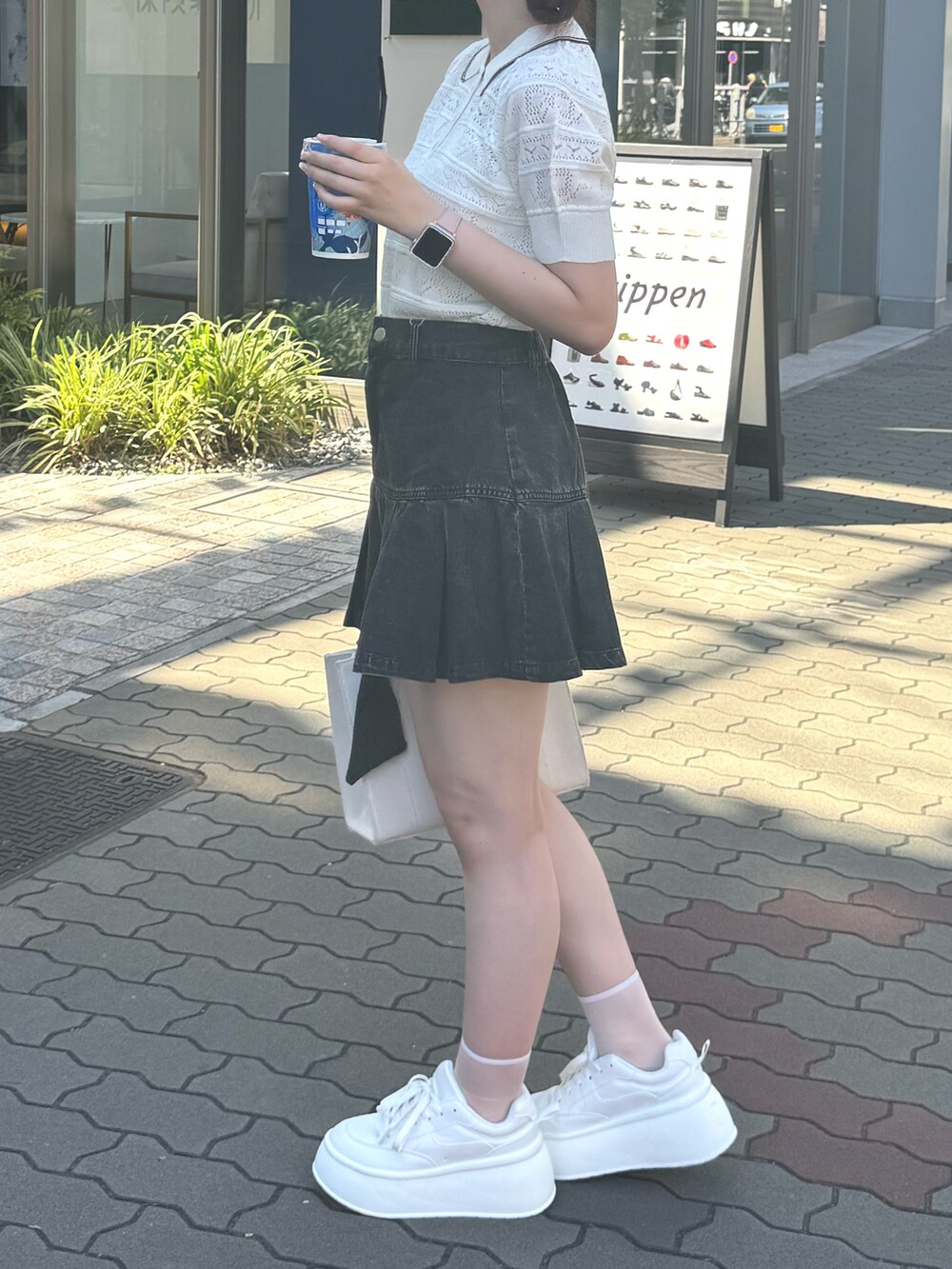 ホワイト系のニット/セーター、ブラック系のスカート、ホワイト系のバッグを着用したレディースの夏コーディネートの2枚目の写真