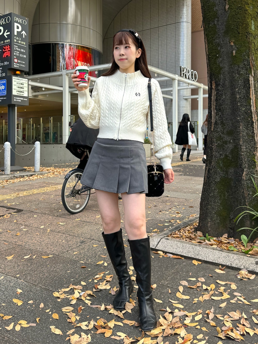 ホワイト系のニット/セーター、グレー系のスカート、ブラック系のショルダーバッグを着用したレディースの冬コーディネートの4枚目の写真