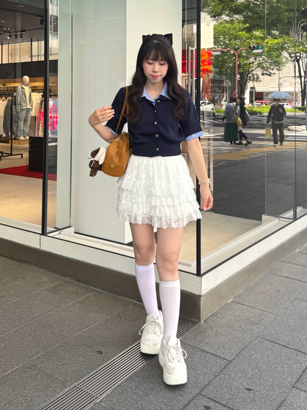 ブルー系のニット/セーター、ホワイト系のスカート、ホワイト系のスニーカーを着用したレディースの春コーディネートの2枚目の写真