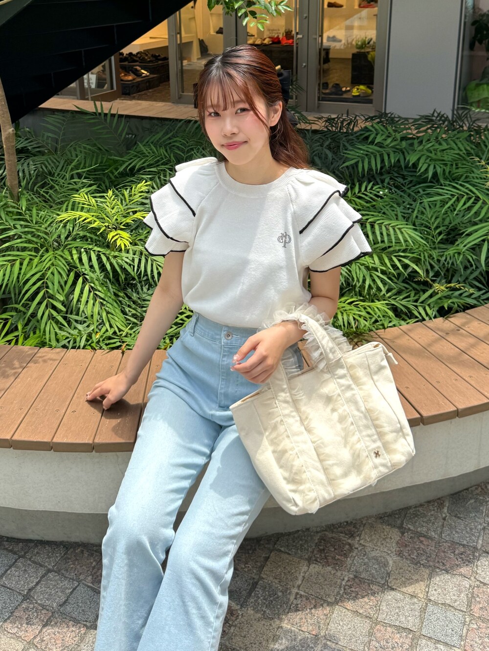 ホワイト系のニット/セーター、ブルー系のデニムパンツ、ホワイト系のトートバッグを着用したレディースの夏コーディネートの4枚目の写真