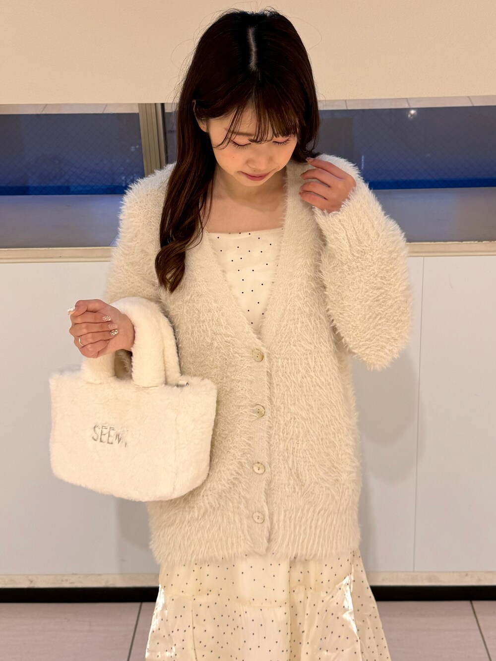 ホワイト系のカーディガン/ボレロ、ホワイト系のワンピース、ホワイト系のブーツを着用したレディースの冬コーディネートの4枚目の写真