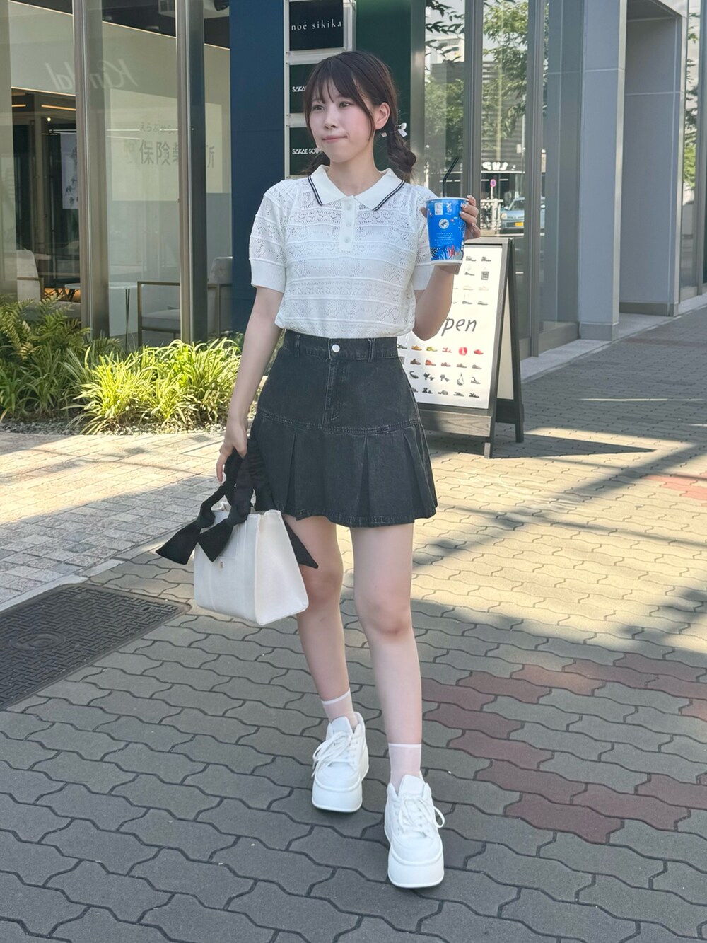 ホワイト系のニット/セーター、ブラック系のスカート、ホワイト系のスニーカーを着用したレディースの夏コーディネートの2枚目の写真