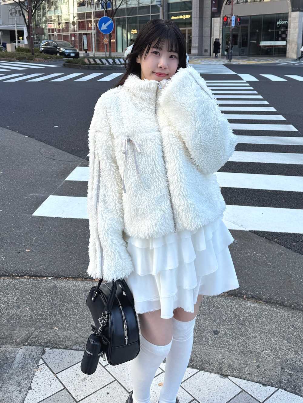 ホワイト系のブルゾン、ホワイト系のスカート、ブラック系のハンドバッグを着用したレディースの冬コーディネートの2枚目の写真