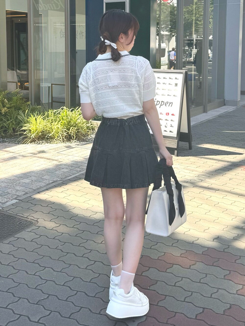 ホワイト系のニット/セーター、ブラック系のスカート、ホワイト系のバッグを着用したレディースの夏コーディネートの3枚目の写真