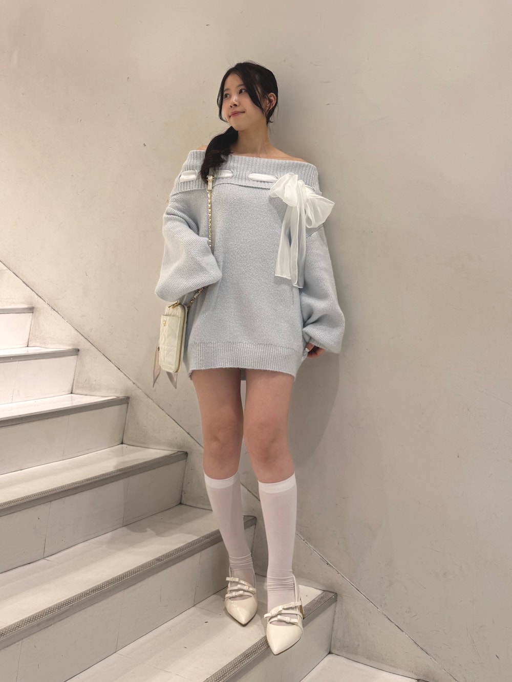 ブルー系のワンピース、ホワイト系のショルダーバッグ、ホワイト系のパンプスを着用したレディースの冬コーディネートの3枚目の写真