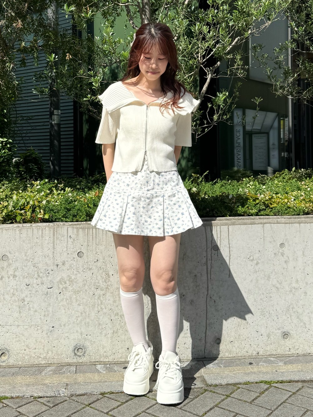 ホワイト系のニット/セーター、ブルー系のスカート、ホワイト系のスニーカーを着用したレディースの春コーディネートの3枚目の写真