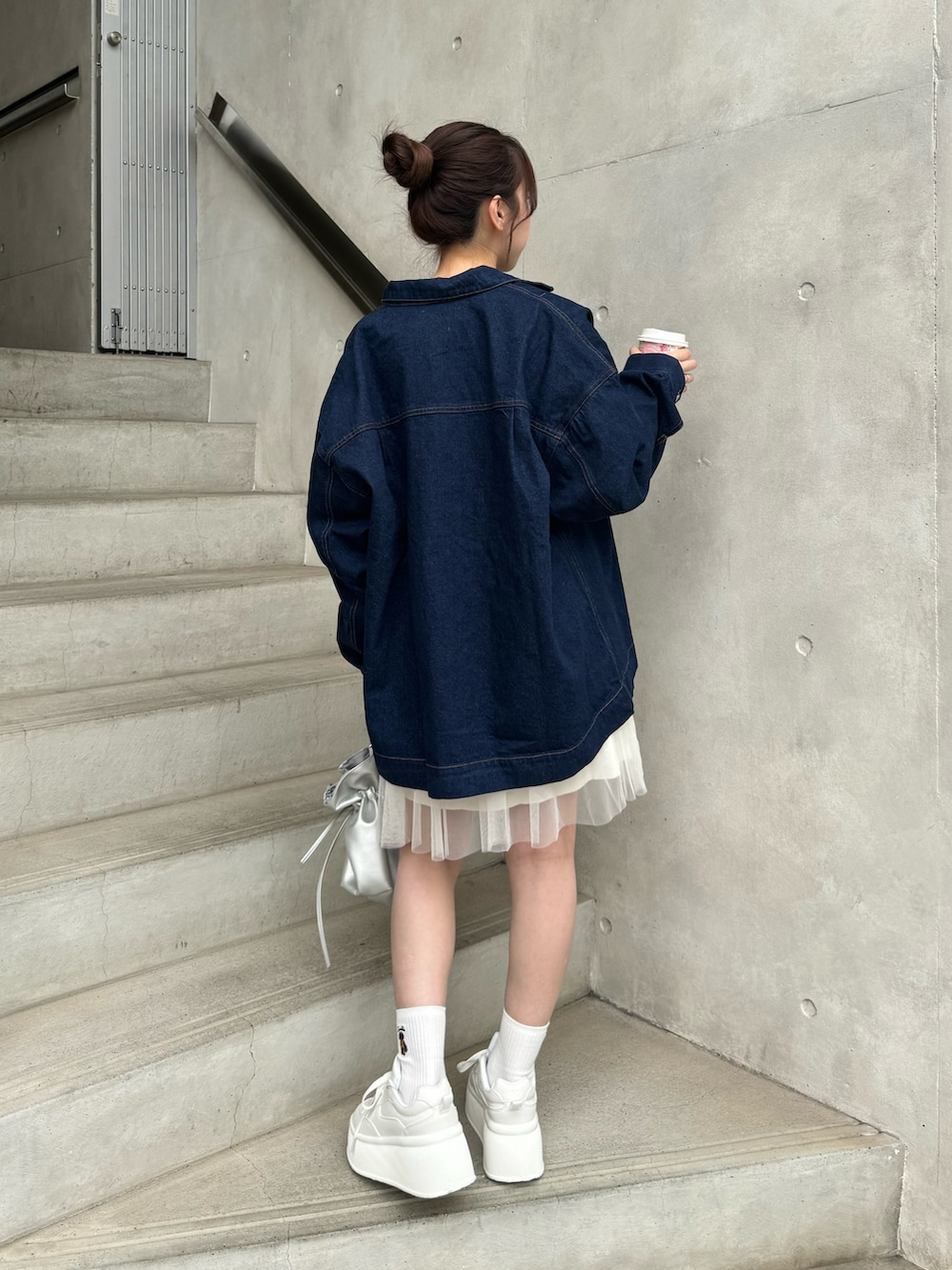 ブルー系のデニムジャケット、ホワイト系のトップス、ホワイト系のスニーカーを着用したレディースの冬コーディネートの4枚目の写真