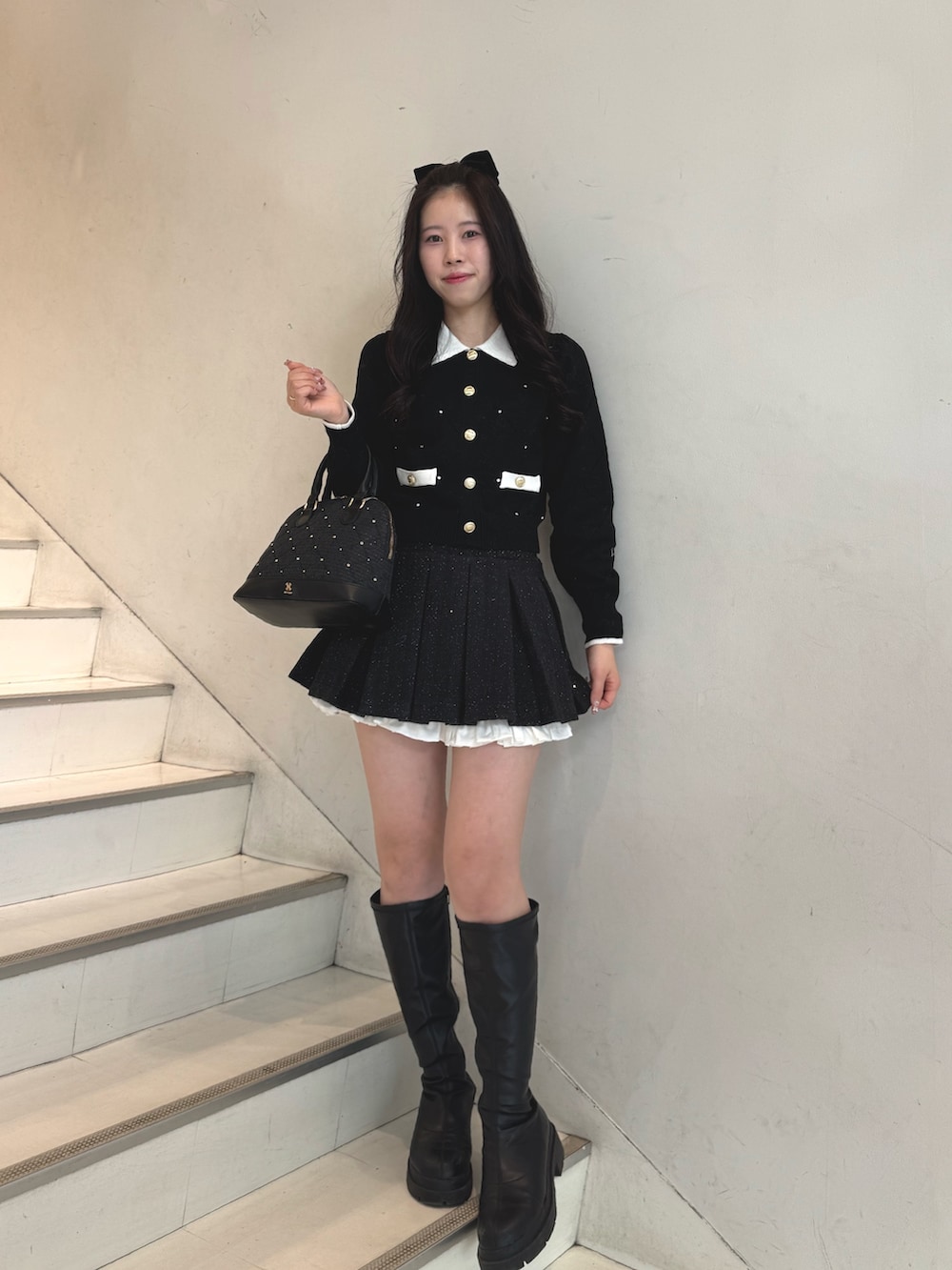 ブラック系のニット/セーター、ブラック系のスカート、ブラック系のハンドバッグを着用したレディースの冬コーディネートの3枚目の写真