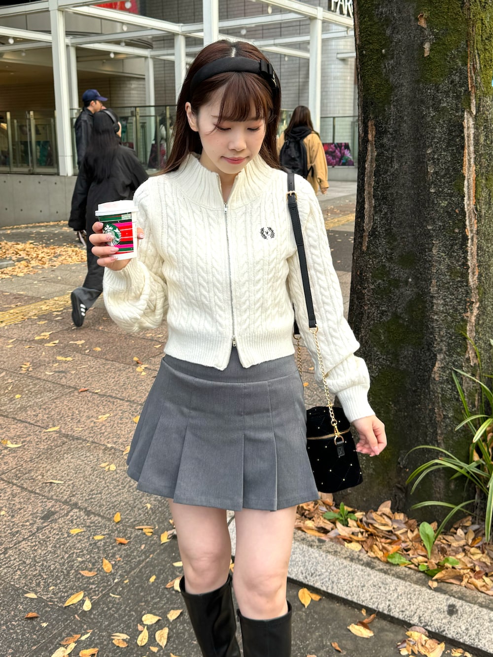 ホワイト系のニット/セーター、グレー系のスカート、ブラック系のショルダーバッグを着用したレディースの冬コーディネートの2枚目の写真