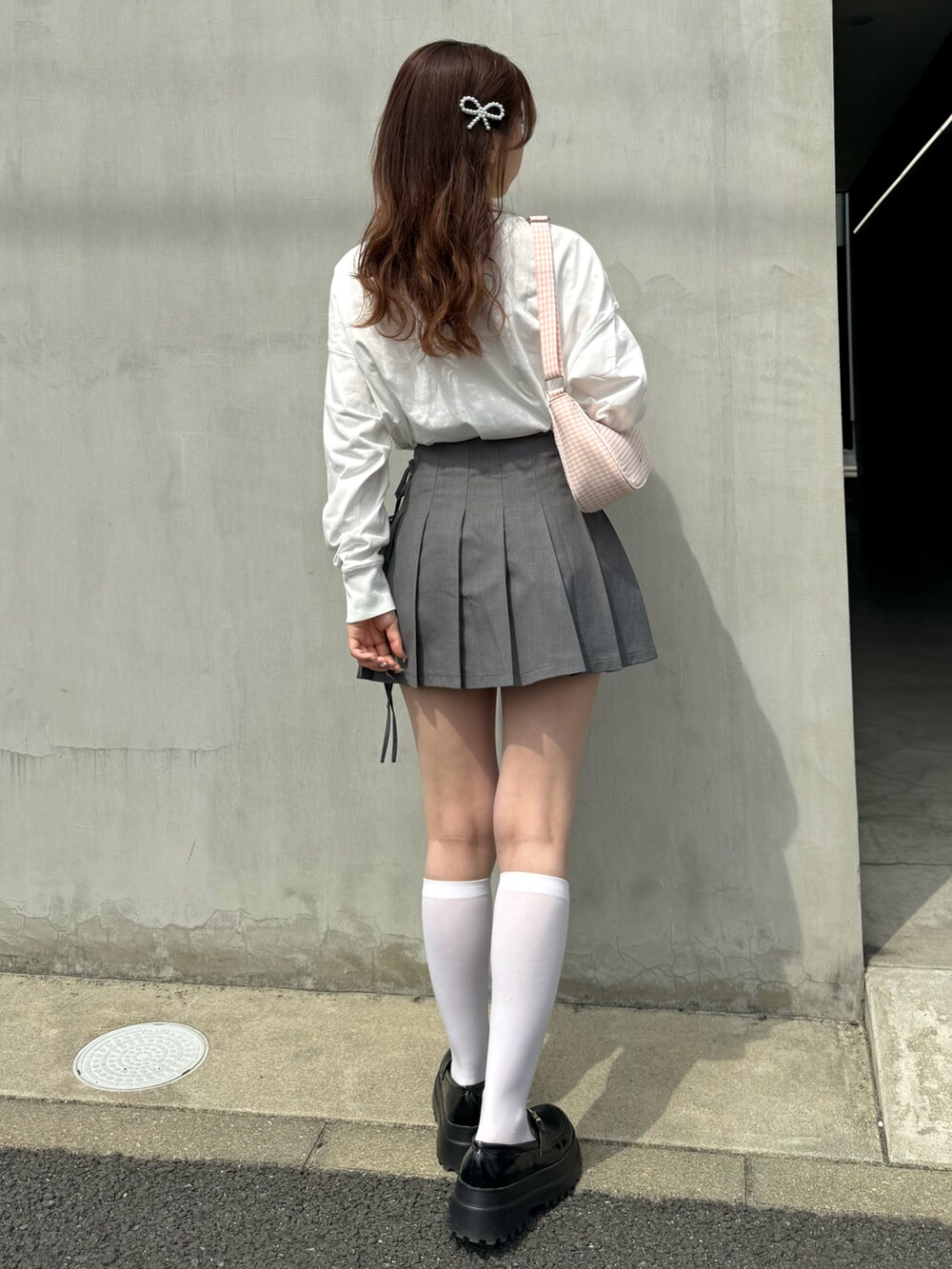 ホワイト系のTシャツ/カットソー、グレー系のスカート、ピンク系のショルダーバッグを着用したレディースの春コーディネートの2枚目の写真