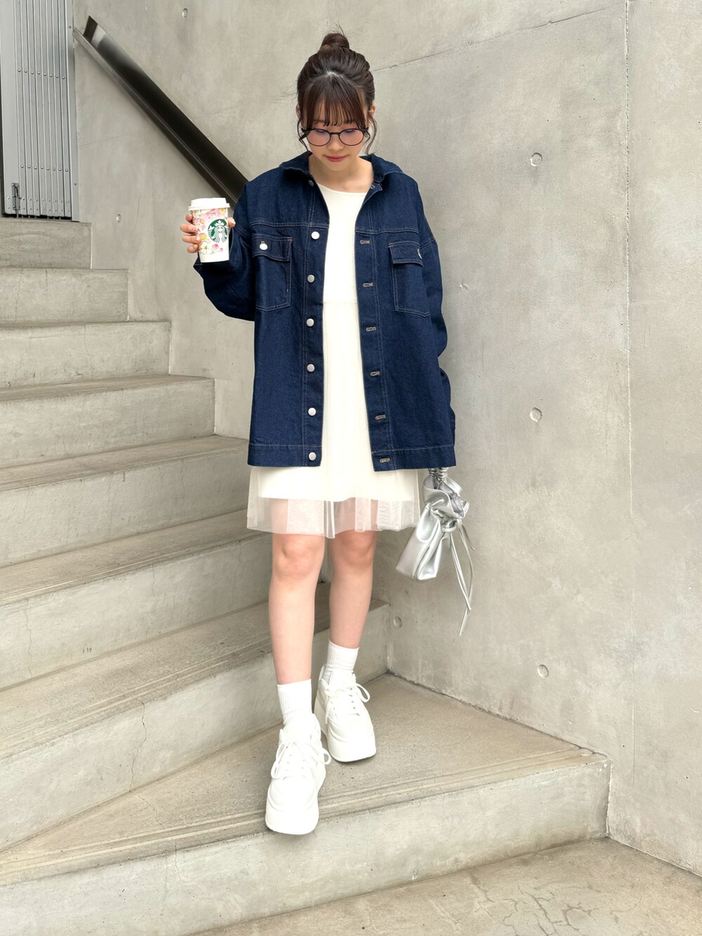 ブルー系のデニムジャケット、ホワイト系のトップス、ホワイト系のスニーカーを着用したレディースの冬コーディネートの3枚目の写真