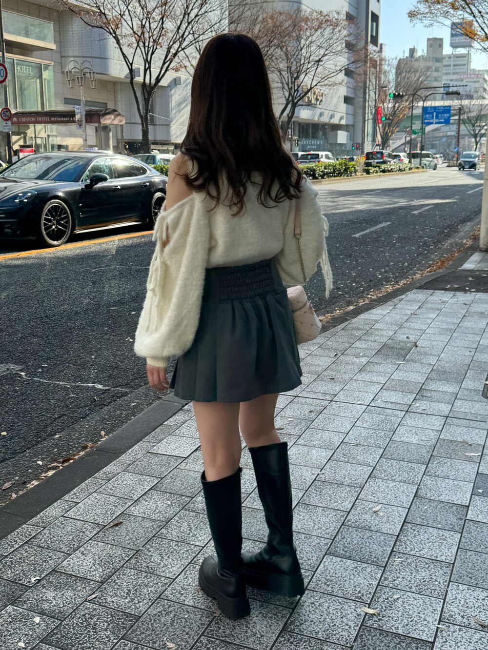 ホワイト系のニット/セーター、グレー系のスカート、ピンク系のショルダーバッグを着用したレディースの冬コーディネートの3枚目の写真