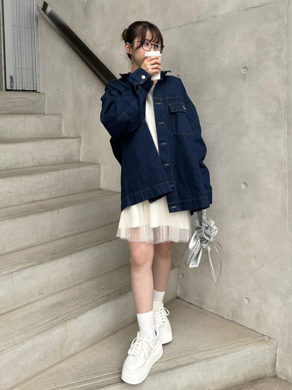 ブルー系のデニムジャケット、ホワイト系のトップス、ホワイト系のスニーカーを着用したレディースの冬コーディネートの2枚目の写真