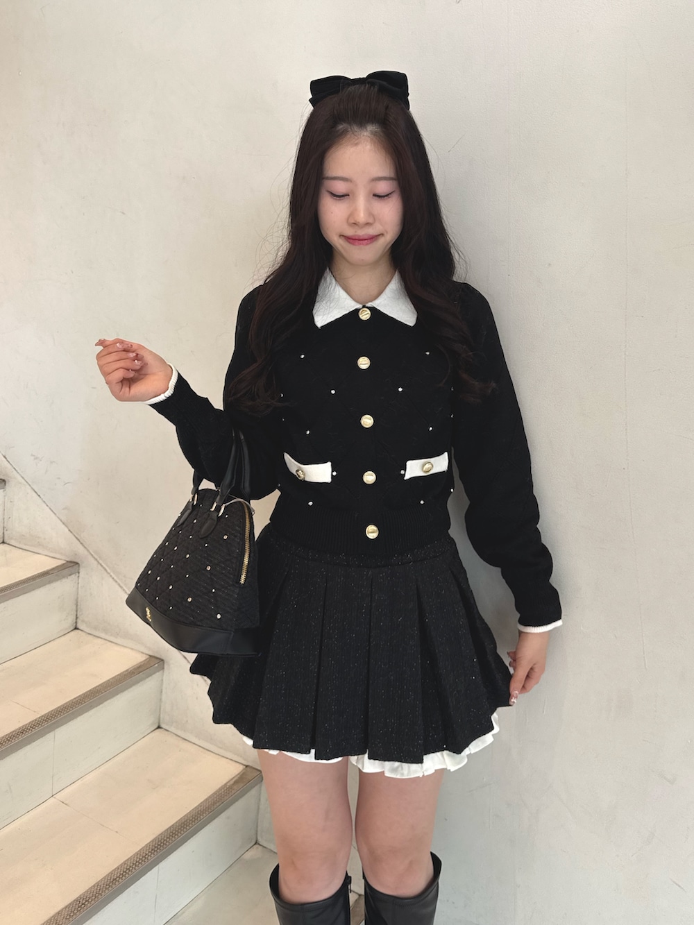 ブラック系のニット/セーター、ブラック系のスカート、ブラック系のハンドバッグを着用したレディースの冬コーディネートの2枚目の写真