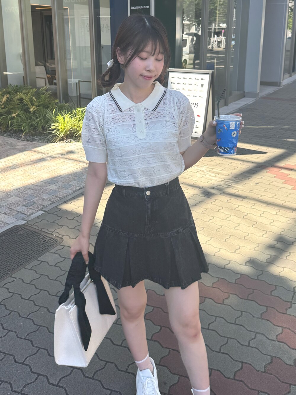 ホワイト系のニット/セーター、ブラック系のスカート、ホワイト系のバッグを着用したレディースの夏コーディネートの4枚目の写真
