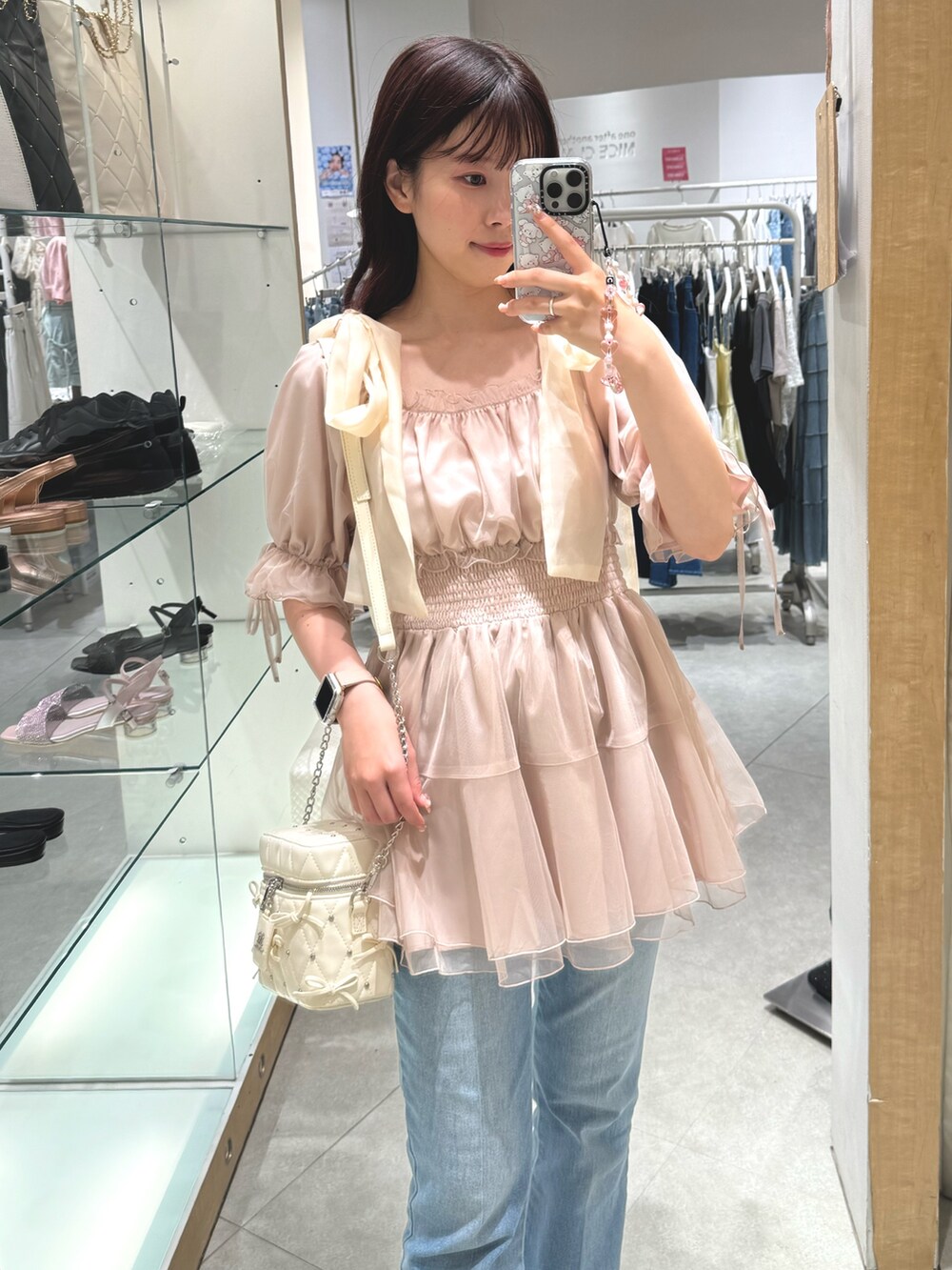 ホワイト系のシャツ/ブラウス、ホワイト系のショルダーバッグ、ブルー系のデニムパンツを着用したレディースの夏コーディネートの2枚目の写真