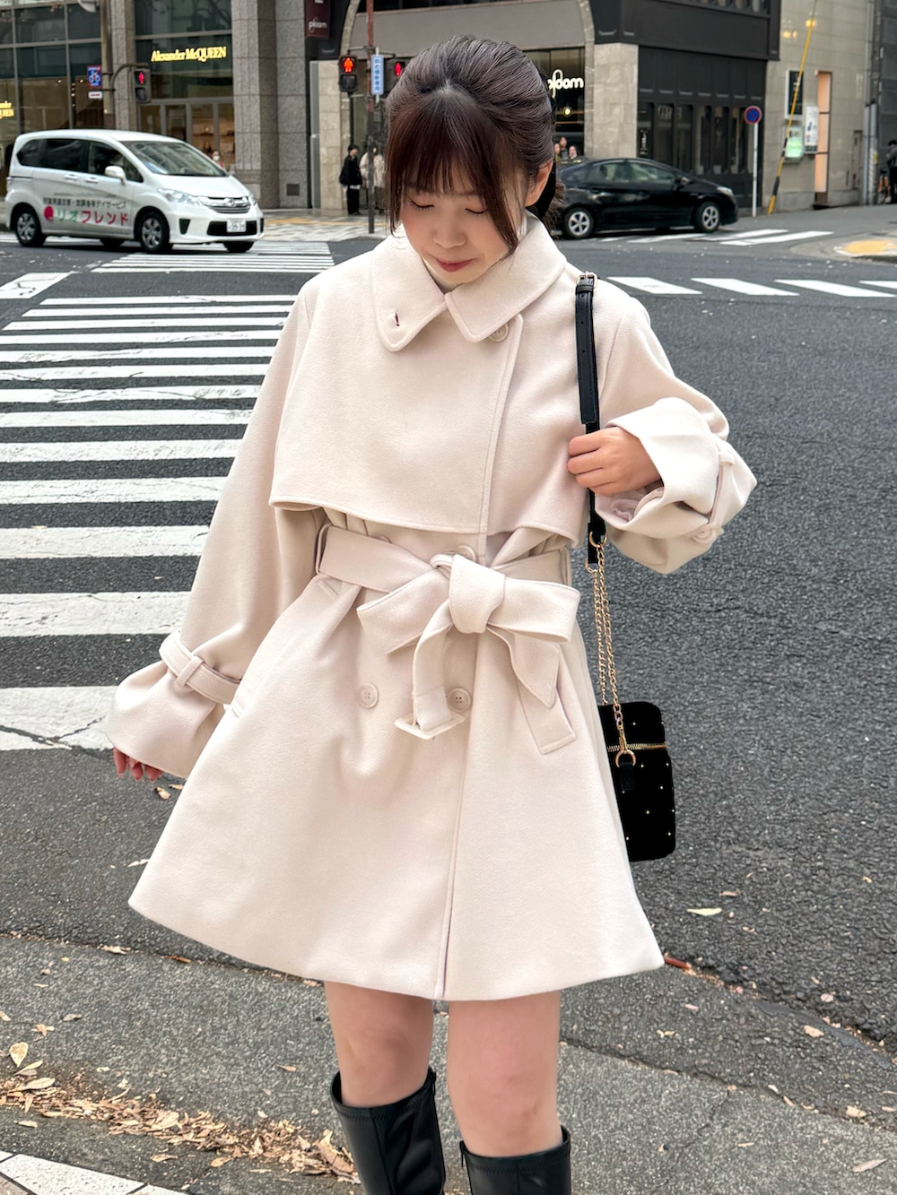 ホワイト系のピーコート、ブラック系のショルダーバッグを着用したレディースの冬コーディネートの3枚目の写真