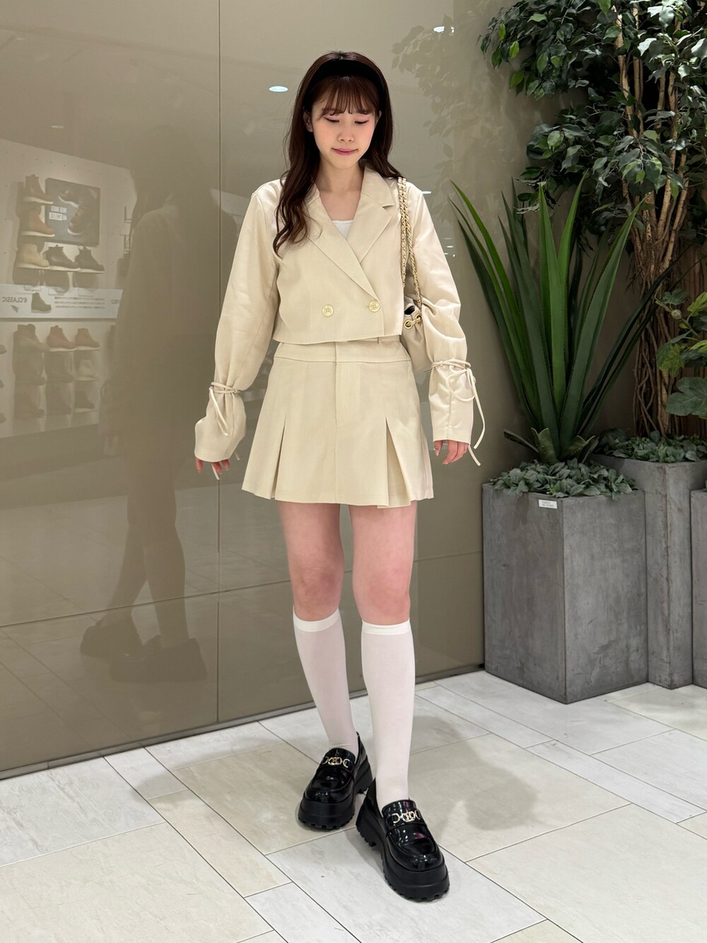 ホワイト系のテーラードジャケット、ホワイト系のスカート、ベージュ系のショルダーバッグを着用したレディースの春コーディネートの2枚目の写真