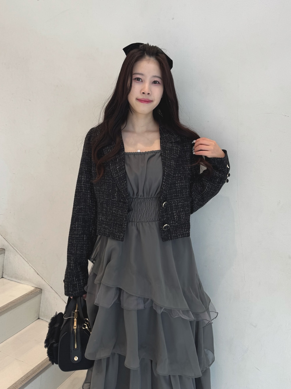 ブラック系のテーラードジャケット、グレー系のワンピース、ブラック系のショルダーバッグを着用したレディースの冬コーディネートの2枚目の写真