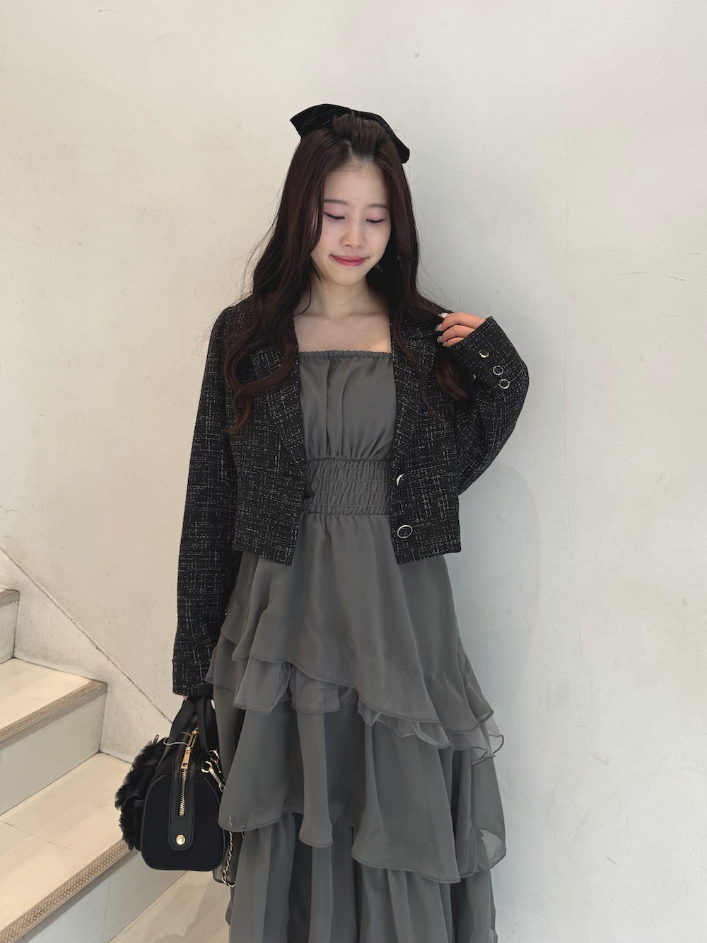 ブラック系のテーラードジャケット、グレー系のワンピース、ブラック系のショルダーバッグを着用したレディースの冬コーディネートの4枚目の写真