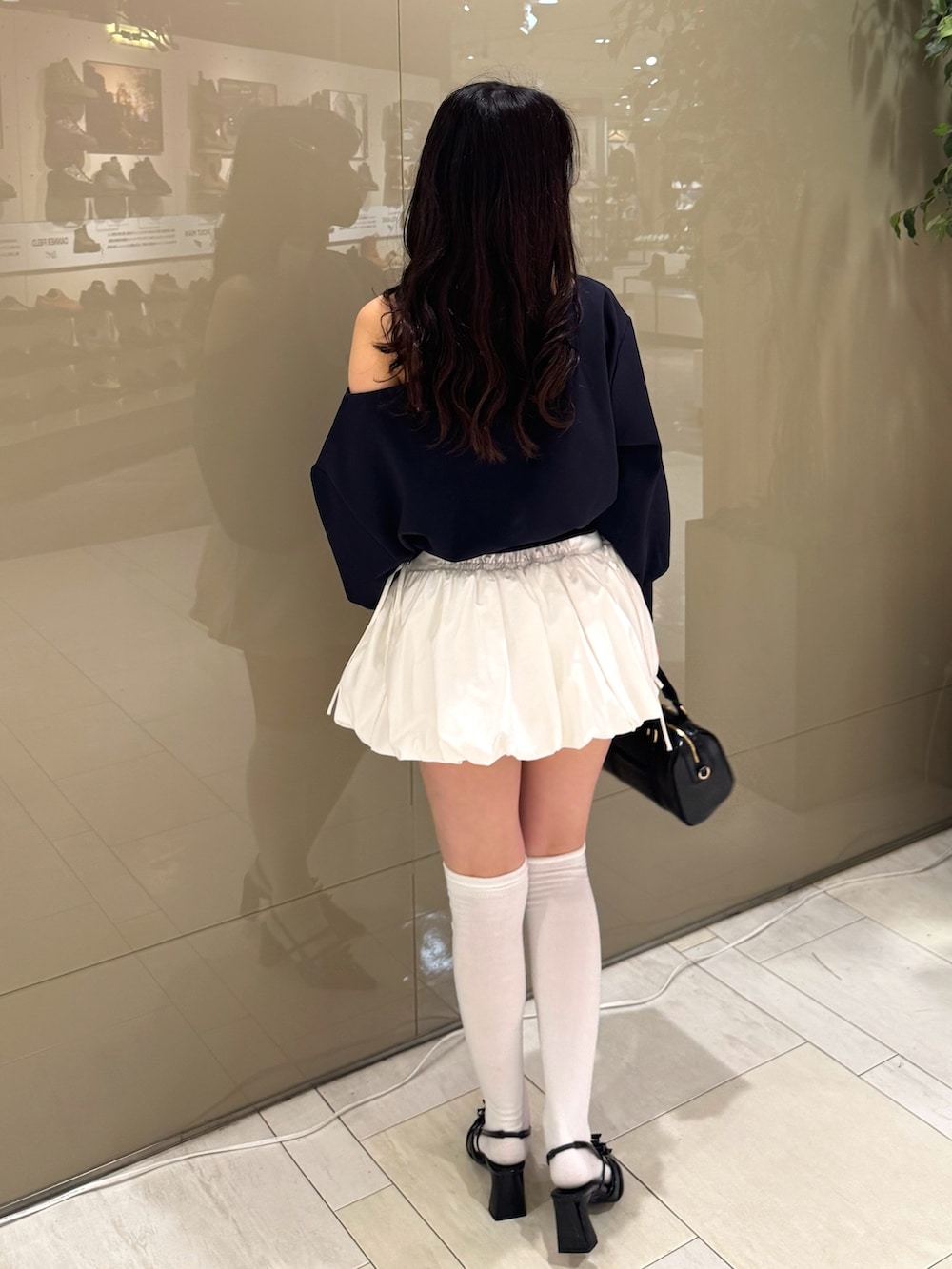 ブルー系のTシャツ/カットソー、ホワイト系のスカート、ブラック系のボストンバッグを着用したレディースの冬コーディネートの3枚目の写真