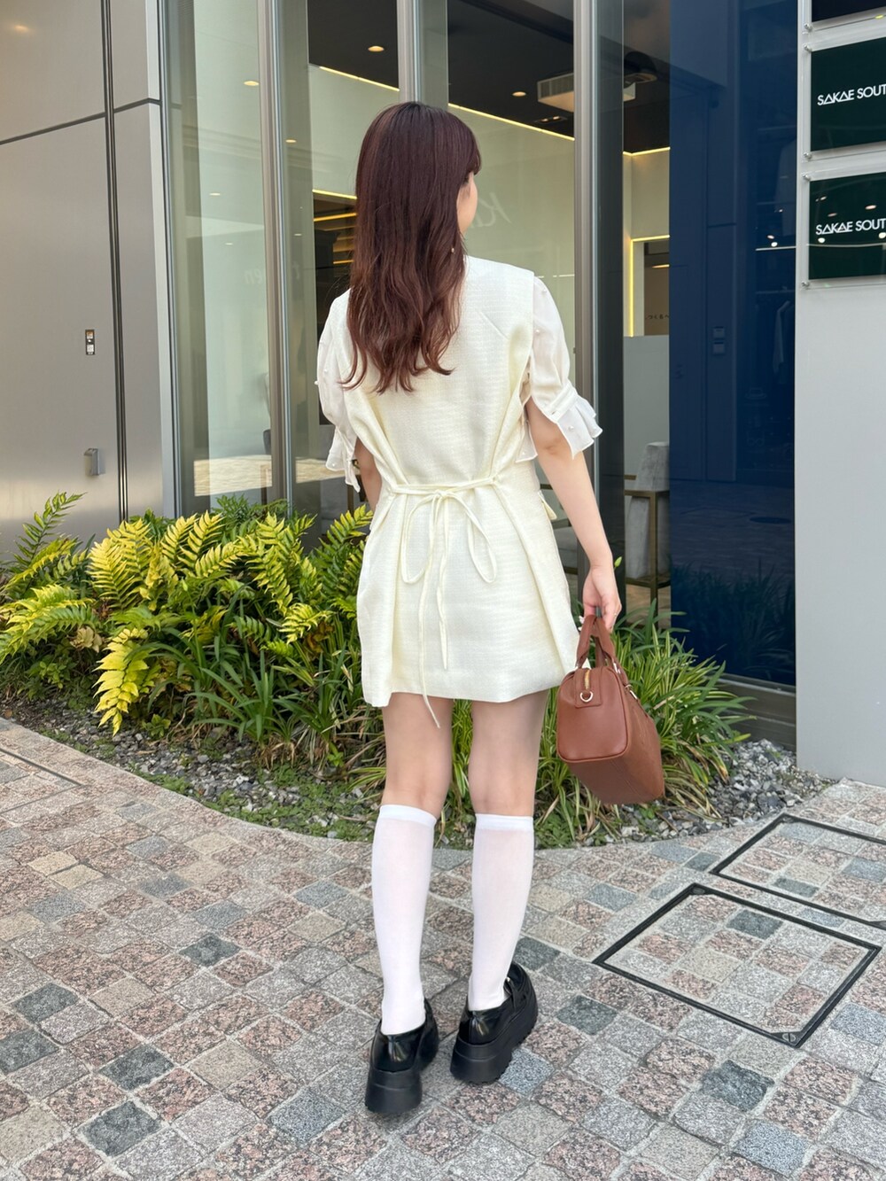 ホワイト系のシャツ/ブラウス、ホワイト系のベスト、ブラウン系のボストンバッグを着用したレディースの夏コーディネートの3枚目の写真
