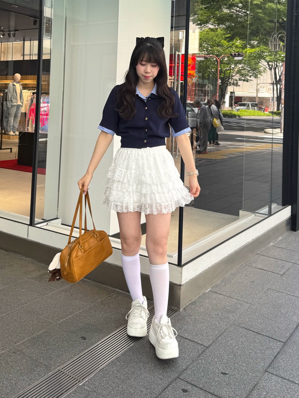 ブルー系のニット/セーター、ホワイト系のスカート、ホワイト系のスニーカーを着用したレディースの春コーディネートの5枚目の写真