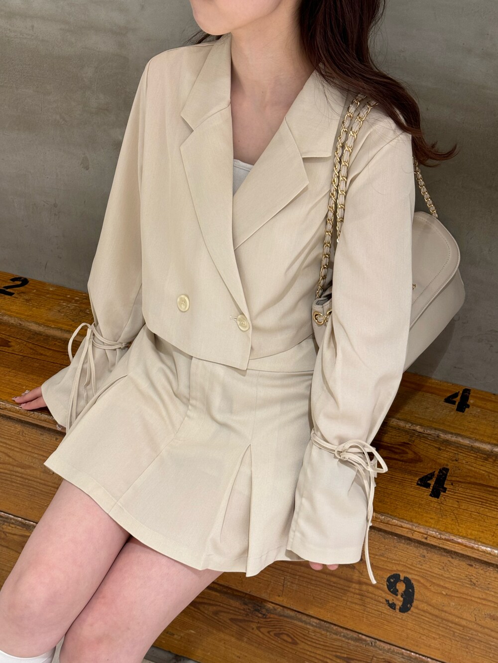 ホワイト系のテーラードジャケット、ホワイト系のスカート、ベージュ系のショルダーバッグを着用したレディースの春コーディネートの5枚目の写真