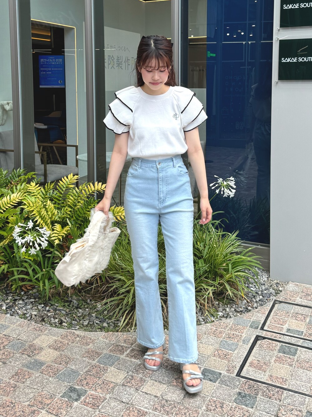 ホワイト系のニット/セーター、ホワイト系のトートバッグ、ブルー系のデニムパンツを着用したレディースの夏コーディネートの4枚目の写真