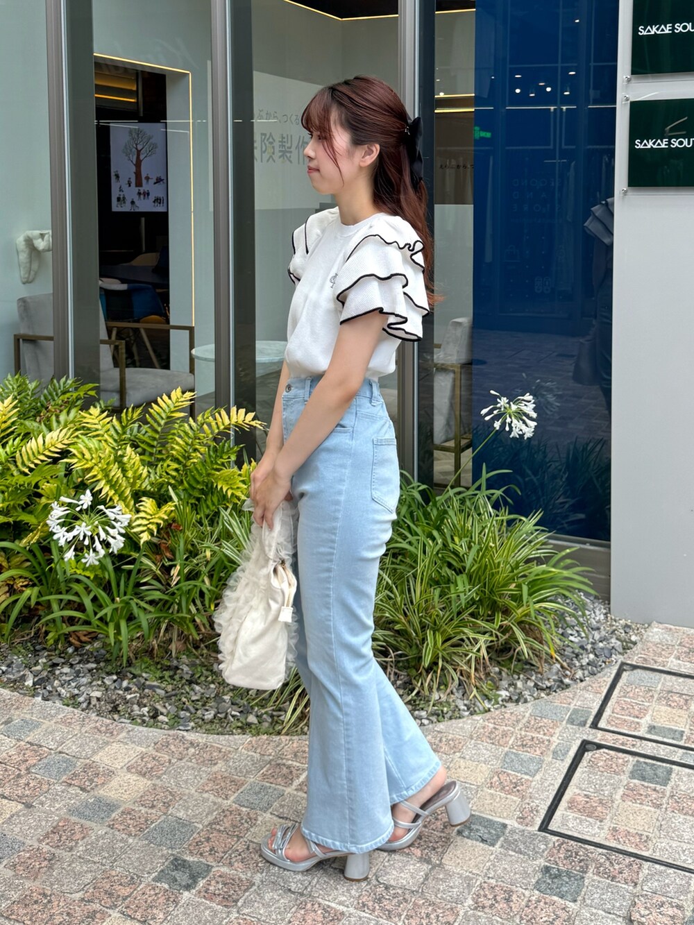 ホワイト系のニット/セーター、ブルー系のデニムパンツ、ホワイト系のトートバッグを着用したレディースの夏コーディネートの2枚目の写真