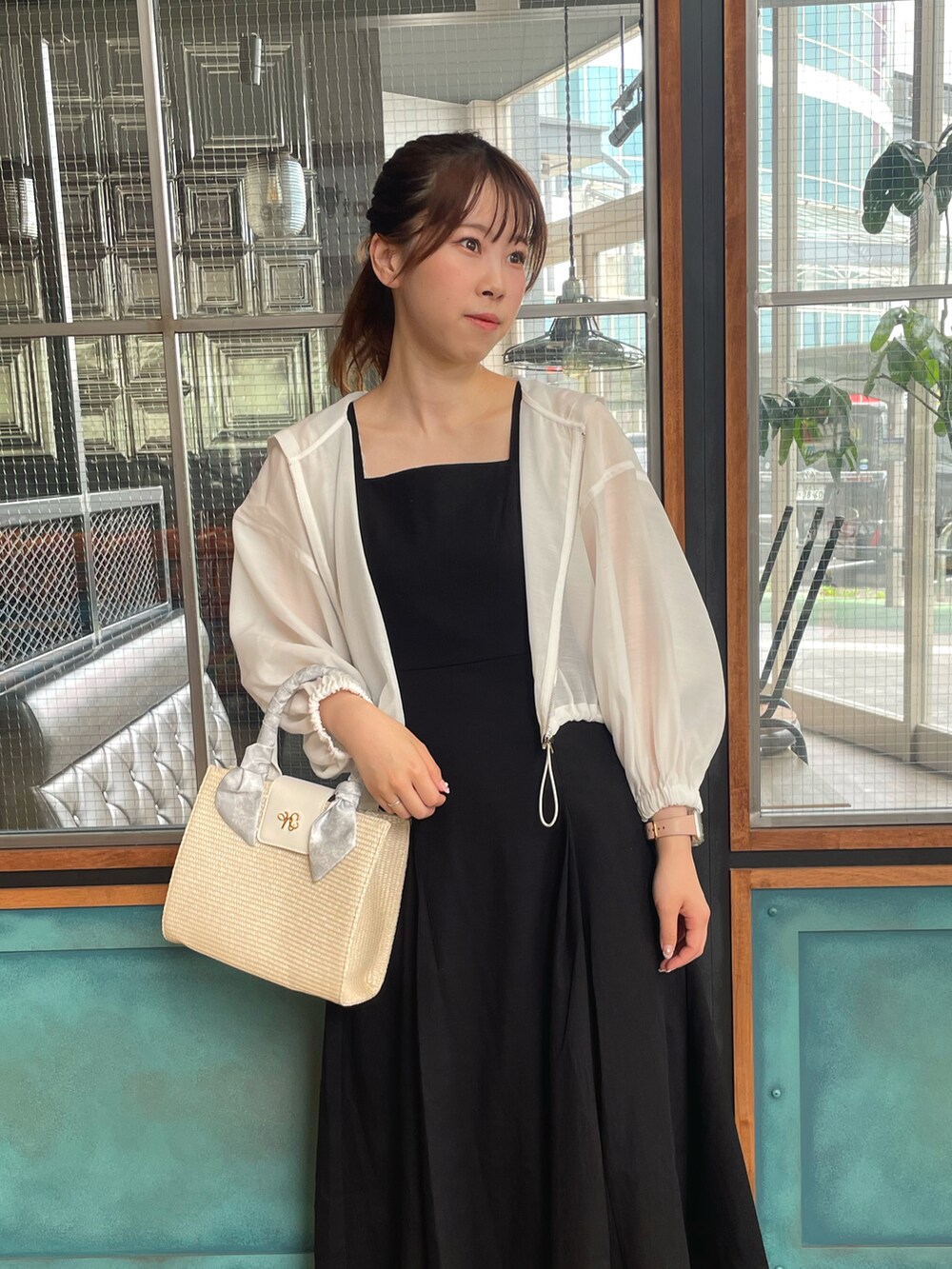 ホワイト系のマウンテンパーカー、ブラック系のワンピース、ホワイト系のショルダーバッグを着用したレディースの春コーディネートの3枚目の写真