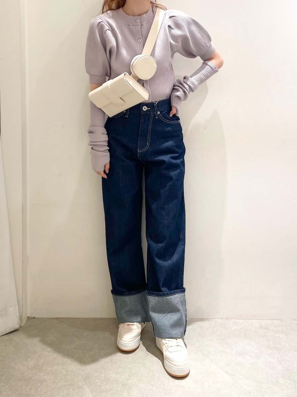 パープル系のニット/セーター、ホワイト系のショルダーバッグ、ブルー系のデニムパンツを着用したレディースの秋コーディネートの2枚目の写真