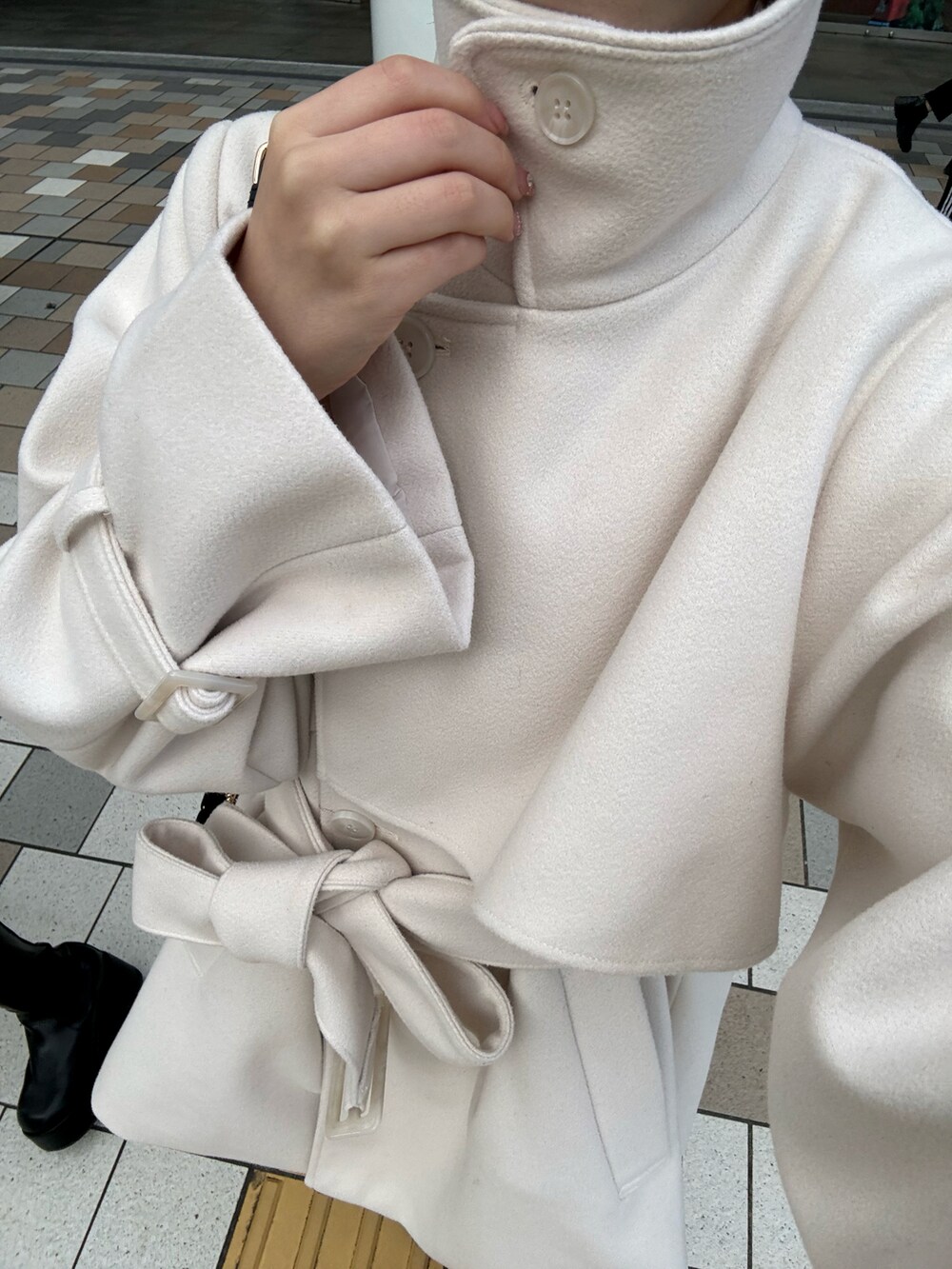 ホワイト系のピーコート、ブラック系のショルダーバッグを着用したレディースの冬コーディネートの5枚目の写真