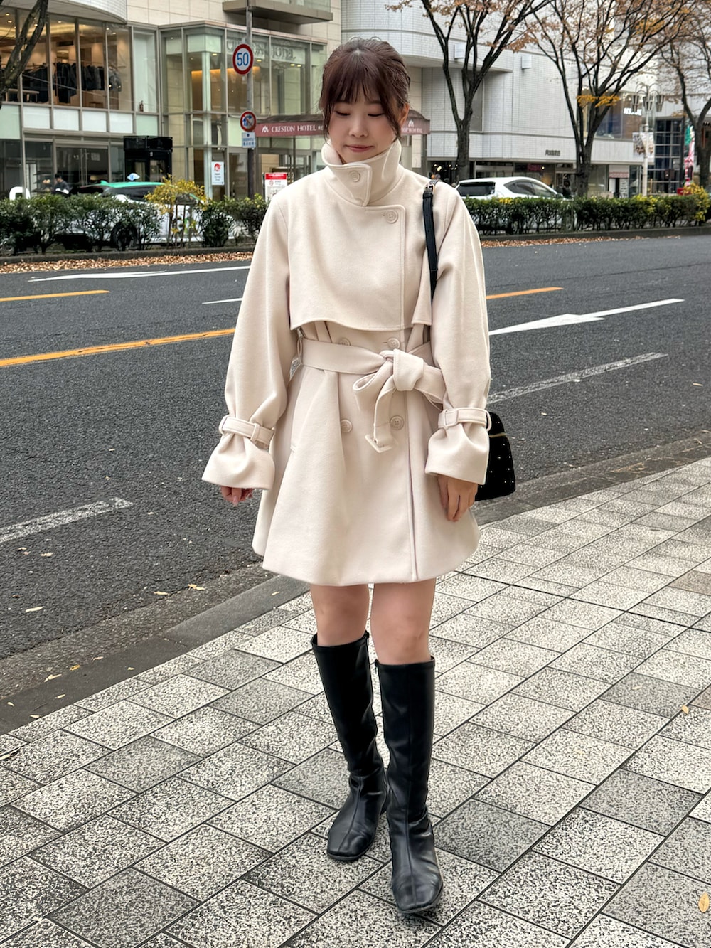 ホワイト系のピーコート、ブラック系のショルダーバッグを着用したレディースの冬コーディネートの4枚目の写真